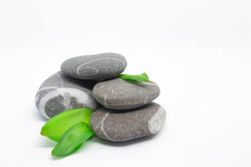 Obraz na płótnie Canvas Pebbles on a white background. Stones with natural striped pattern. Four small stones lie on top of each other.Pebbles decorated with green leaves.