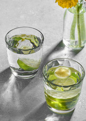 Water fitness detox with lime on a light grey background. Hard sun light and shadow. Soda coctail