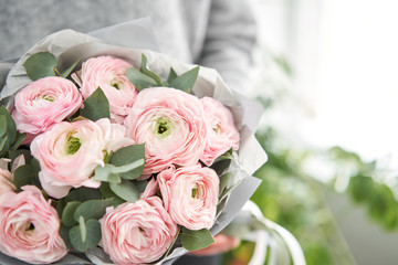 Bunch pale pink ranunculus flowers with green eucalyptus. The work of the florist at a flower shop.