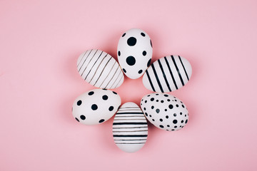 Many easter eggs on trendy pink pastel background. Eggs are hand-drawn. Flat lay style.