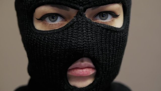 Close-up portrait of sexy woman dressed hacker black balaclava mask with beautiful eyes, robbery concept