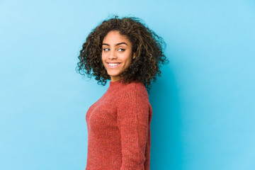 Young african american curly hair woman looks aside smiling, cheerful and pleasant.