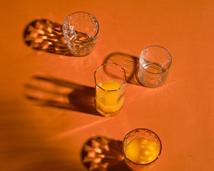 glass with orange juice.  Sun hard light shadow reflection. Tropical summer minimalism concept