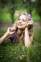 Beautiful blonde girl is lying in the grass and laughing.