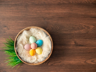 Colorful Easter eggs in nest and spring flowers on wooden table. Easter holiday decorations , Easter concept background.