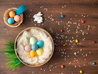 Fototapeta na wymiar Colorful Easter eggs in nest, spring flowers and candy on wooden table. Easter holiday decorations , Easter concept background.