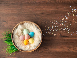 Colorful Easter eggs in nest and spring flowers on wooden table. Easter holiday decorations , Easter concept background.