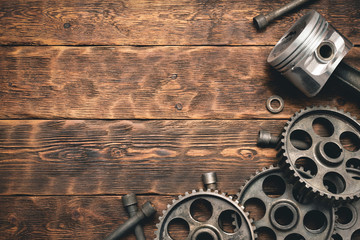 Old car spare parts on brown wooden workbench flat lay background with copy space.