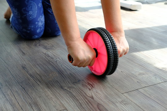woman in gym with gymnastic wheel roller does exercises for belly