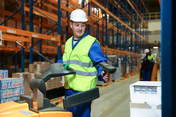 warehouse worker on a forklift scans a box of goods with a barcode scanner