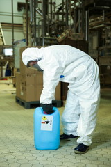 worker in white chemical protection suit and mask with chemical canister at the factory