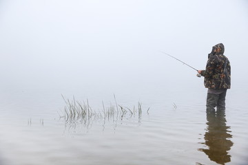 fisherman holding fishing rod on the river in fog