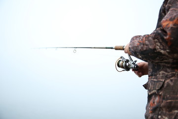 fisherman holding fishing rod on the river in fog close up with copy space