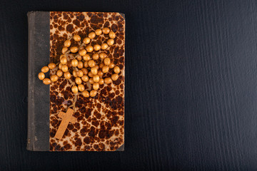 Wooden rosary arranged on an old book. Accessories for prayer in a Christian church.