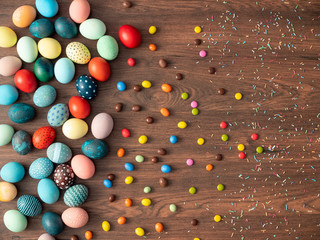 Fototapeta na wymiar Colorful Easter eggs on wooden table with candies. Easter holiday decorations , Easter concept background.