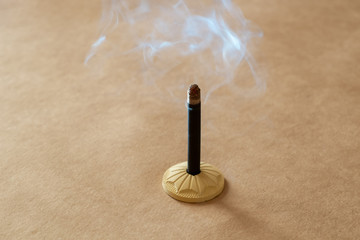 the incense stick stands in a clay stand and emits fragrant smoke