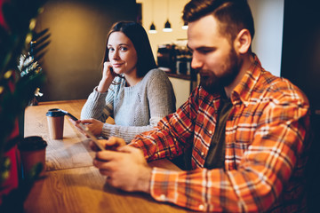 Content young people browsing smartphone and looking at camera in cafe