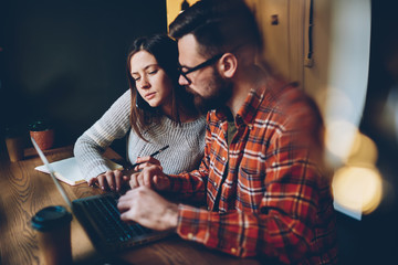 Serious students studying information on laptop at table in cafe