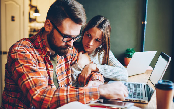 Young Woman Comforting Upset Boyfriend During Work In Cafe