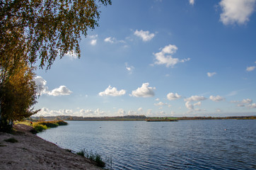 autumn landscape. stand and look into the distance standing on the shore of the lake. think about life and the infinity of being. the clouds float across the sky slightly reflecting in the water.
