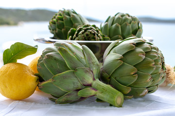 Obraz premium Cooking with fresh green artichokes heads, tasty vegetarian food, on open kitchen with sea view