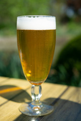 Golden belgium triple beer in glass served outdoor on table