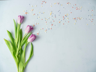 Purple tulips and candies on bright background. Decorations and background.