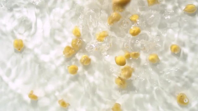 Dried uncooked chickpeas falling in slow motion into water. Vegetarian food packed with minerals, iron, magnesium, potassium and other minerals. Healthy source of fiber.