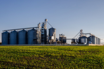 Obraz premium A large modern plant for the storage and processing of grain crops. view of the granary on a sunny day against the blue sky. End of harvest season.