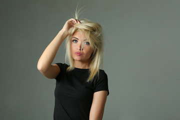 young beautiful blonde woman in  black t-shirt posing on a grey background