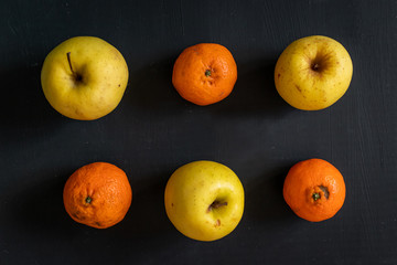 yellow apples and oranges in rows over a dark background