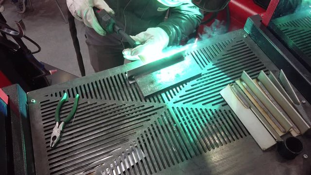 The welder is welding metal parts. Workplace of the welder