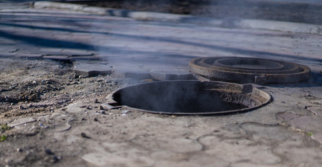 Steam, smoke, and gas flow from the open hatch on the street.