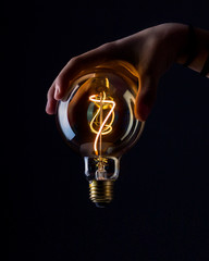 light bulb with hand on black background