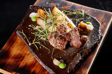 Grilled Beef steak Ribeye with roasted potato on cutting board. With deep-fried onions and tomato sauce.