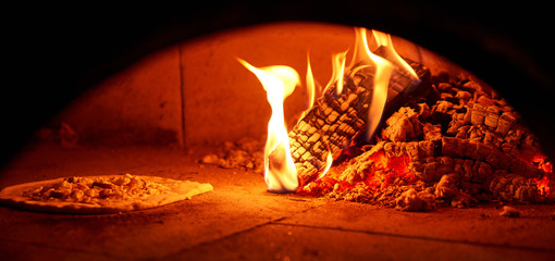 Baked tasty margherita pizza in Traditional wood oven in Naples restaurant, Italy. Original neapolitan pizza. Red hot coal.