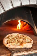 Baked tasty pizza with Gorgonzola and pear, in Traditional wood oven in Naples restaurant, Italy. Original neapolitan pizza. Red hot coal.