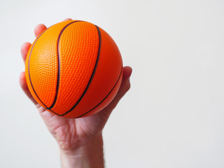 Mini basketball in a hand on a bright background.