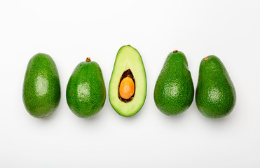 Fresh ripe organic green avocados and halve on white background, top view summer food concept. Minimal flat lay style avocados whole fruit and halve on yellow background.
