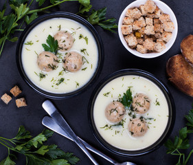 Cheese soup with chicken meatballs and dill and parsley in a bowl