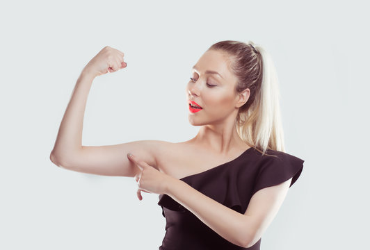 Good, look, my muscles are growing. Young happy woman flexing muscles showing her strength isolated white light blue wall background. Positive emotion facial expression. Weight loss well being concept