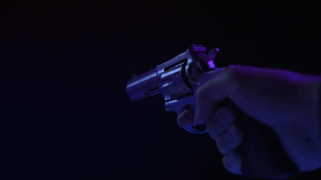 .357 MAGNUM HANDGUN RAISED INTO FRAME.  ECU IN 4K, 10 BIT, 4:2:2.  SIMULATED POLICE CAR LIGHTING.