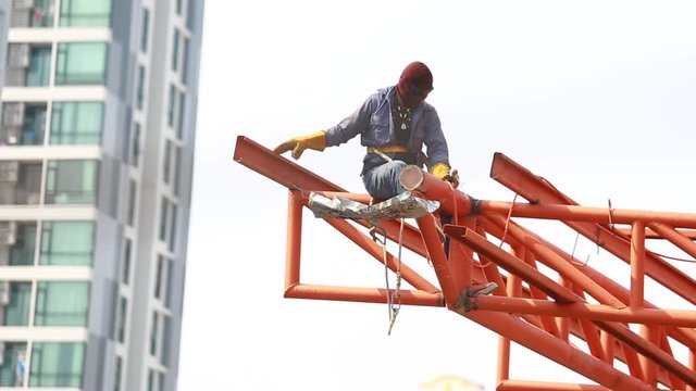 The welding workers at structures site. Worker is welding steel structures. Workers are also working at high altitude with a set of fall protection devices.