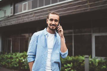 Happy guy talking on smartphone near cottage