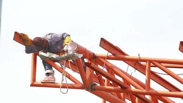 The welding workers at structures site. Worker is welding steel structures. Workers are also working at high altitude with a set of fall protection devices.
