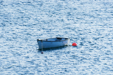 Kleines weißes Boot, an einer roten Boje befestigt in Olshoremore, Schottland