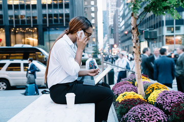 Fototapeta premium Working woman talking on phone with tablet and coffee on street