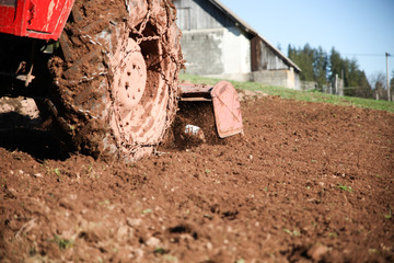An agricultural tractor cultivates fertile soil in a mountain village.-image