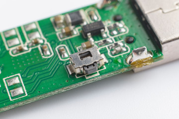 USB wifi adapter. Small button. Green printed electronic circuit board  having small electronic components and chips.