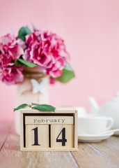 Happy Valentine's Day. Wooden calendar for February 14 with flowers a white cup.